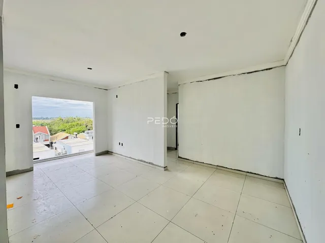 Espaço interno amplo com piso de cerâmica e vista para o exterior.