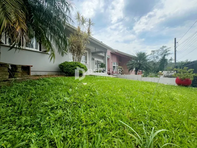 Vista da fachada de uma residência com jardim gramado.