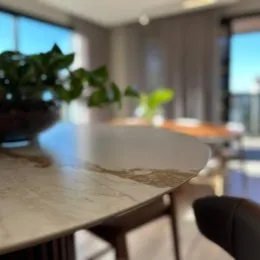 Vista de uma mesa de jantar com uma planta em um ambiente interno.