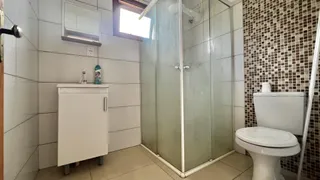 Banheiro com box de vidro, pia e vaso sanitário em azulejos.