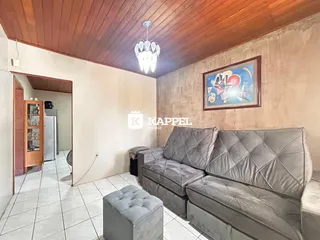 Sala de estar com sofá cinza estofado e teto de madeira aparente.