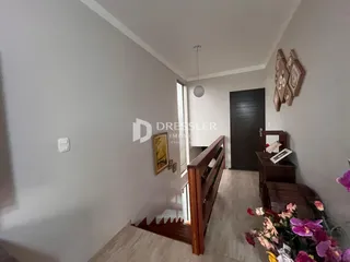 Hall de entrada com piso de madeira e porta escura em imóvel em Lajeado.
