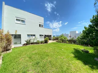 Vista externa de uma casa branca com jardim verde.