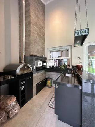 Foto da cozinha com bancadas escuras e exaustor de aço inoxidável.