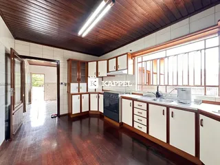 Esta é uma cozinha com armários brancos e piso de madeira.