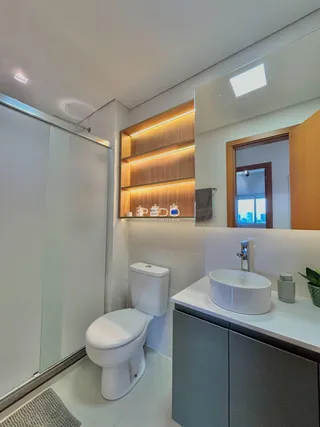 Banheiro moderno com revestimento branco e detalhes em madeira.