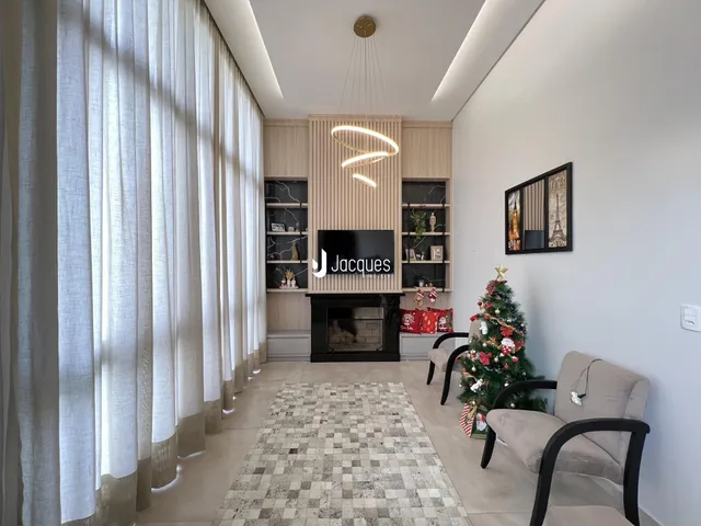 Sala de estar com grandes janelas e lareira em um imóvel no Brasil.