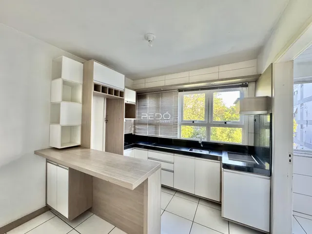 Cozinha moderna com armários brancos e bancada escura em um apartamento no Brasil.