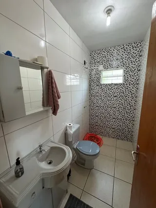 Banheiro com revestimento de azulejos brancos e louças sanitárias.