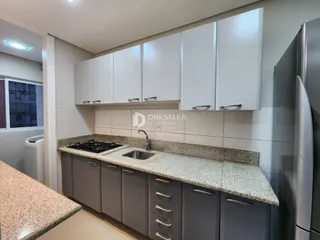 Armários brancos e bancada com pia são visíveis na cozinha.