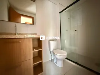 Foto de um banheiro interno com armário e box de vidro transparente.