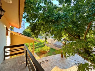 Vista de uma varanda com piso de cerâmica e vegetação ao redor.