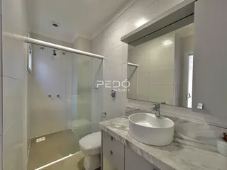 Banheiro moderno com box de vidro e bancada de mármore.