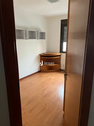 Vista de um corredor com piso de madeira clara em uma residência.