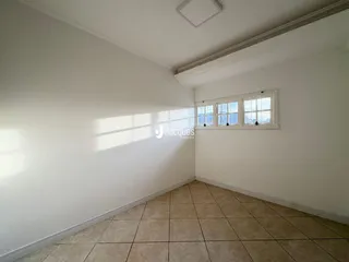 Vista interna de um cômodo com paredes brancas e piso de cerâmica.