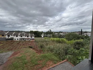 Vista externa de uma propriedade com terreno e vegetação no primeiro plano.