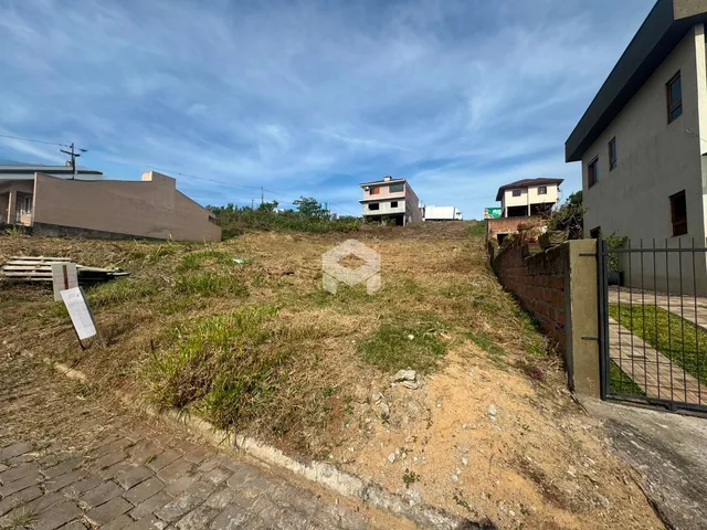 Vista externa de um terreno com declive de terra e muro de tijolos.