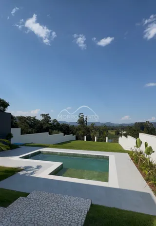 Foto de uma piscina externa com área verde e paisagismo.