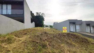 Vista externa de uma propriedade com terreno inclinado coberto por vegetação seca.