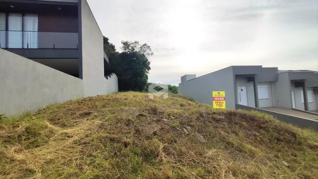 Vista externa de uma propriedade com terreno inclinado coberto por vegetação seca.