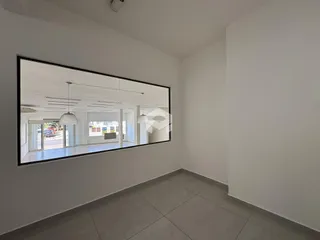 Ambiente interno com parede branca e piso de cerâmica refletido em um espelho grande.