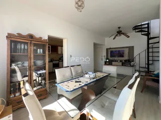 Sala de estar com mesa de vidro e armário de madeira.