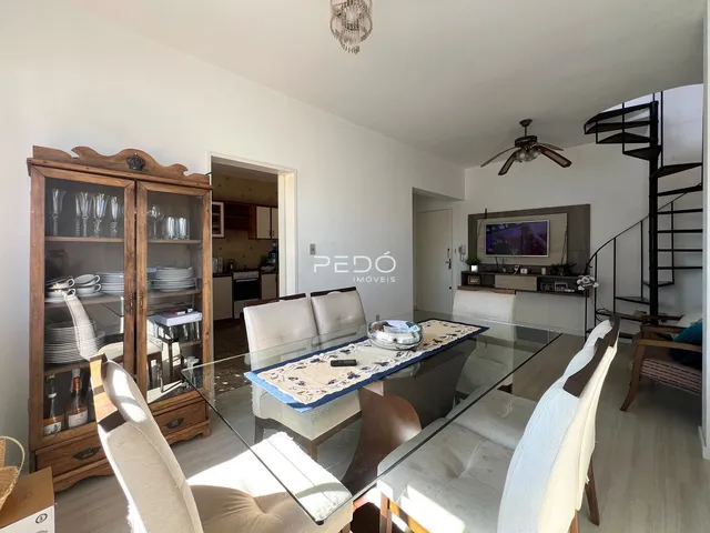 Sala de estar com mesa de vidro e armário de madeira.