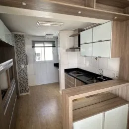 Foto interna de uma cozinha com armários brancos e bancada.