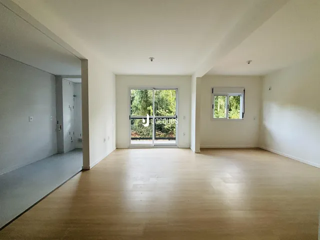 Ambiente interno amplo com piso de madeira clara e portas de vidro.