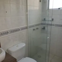 Foto de um banheiro com revestimento de azulejos brancos e box de vidro.