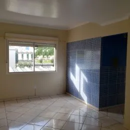 Foto interna de uma sala com piso de cerâmica e janela.