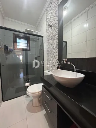 Banheiro moderno com louças brancas e revestimento de cerâmica.