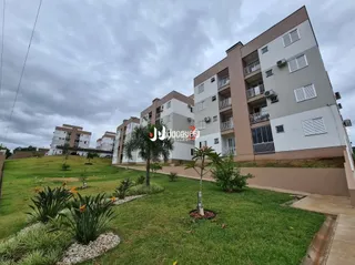 Gramado verde com vegetação na frente de um edifício residencial.