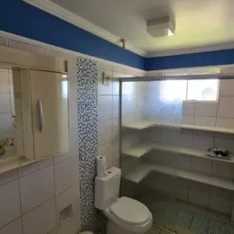 Foto interna de um banheiro com revestimento de azulejos brancos.