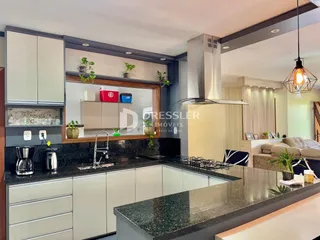 Uma cozinha moderna com armários brancos e bancadas escuras.
