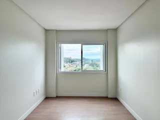 Ambiente interno com piso de madeira e janela com vista para a paisagem.