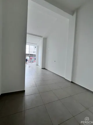 Corredor interno com piso de cerâmica e paredes brancas.