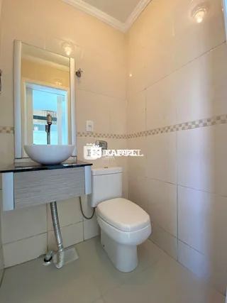 Banheiro com pia e vaso sanitário revestidos de azulejos brancos.