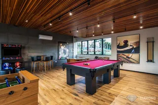 Ambiente amplo com mesa de bilhar e piso de madeira em uma residência.
