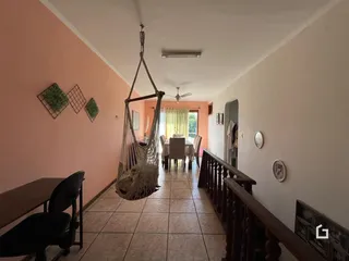 Vista de um corredor com piso de cerâmica e área de jantar em uma residência.