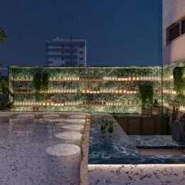 Fachada de um imóvel com vegetação exuberante à noite.