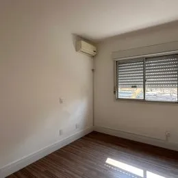 Ambiente interno com parede branca e janela com persiana no quarto.
