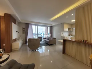 Sala de estar ampla com piso claro e iluminação moderna.