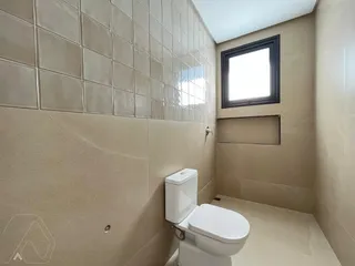 Foto interna de um banheiro com revestimento de azulejos claros.