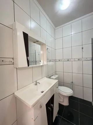 Foto de um banheiro com azulejos brancos e louças sanitárias.