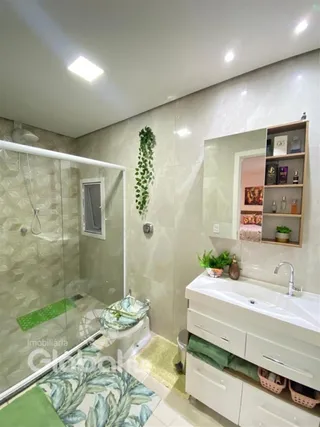 Foto de um banheiro com box de vidro e piso claro.