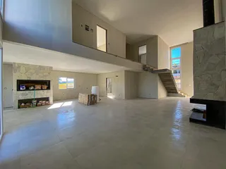 Ambiente interno amplo com escadaria e parede de lareira em uma residência.