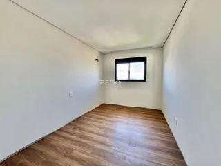 Vista interna de um ambiente com paredes brancas e piso de madeira.