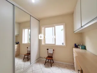 Hall de entrada com janela e cadeira de madeira em ambiente interno.