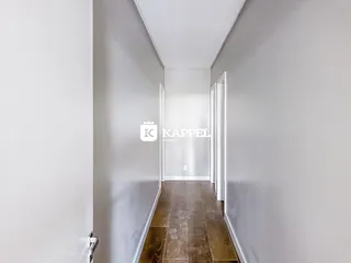 Foto de um corredor longo com paredes brancas e piso de madeira.